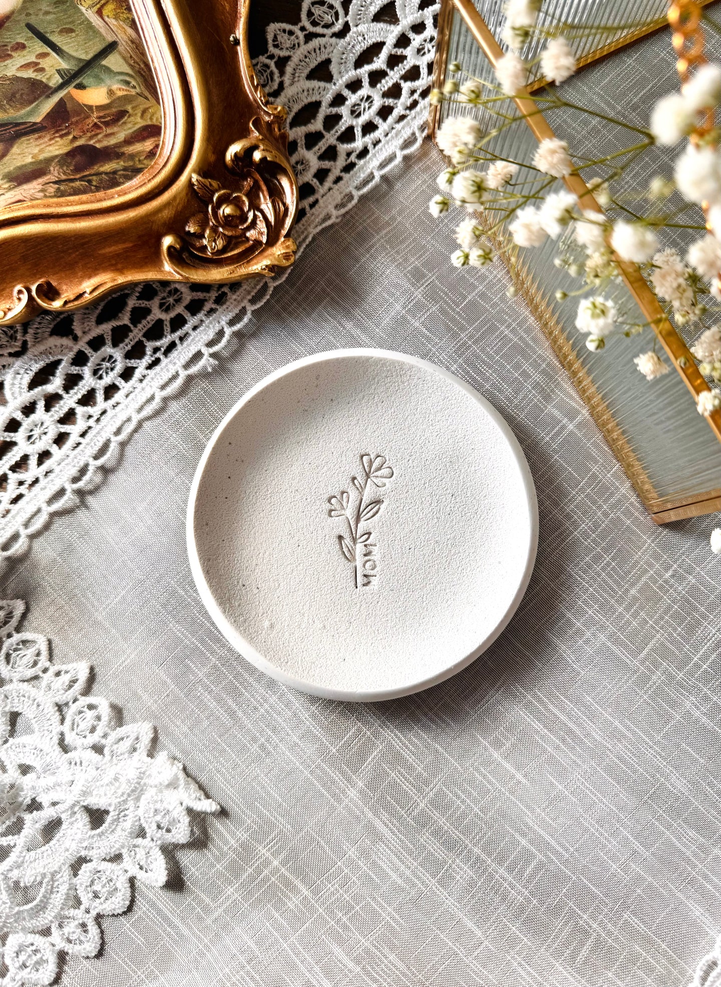 simple ring dish made of speckled white clay with floral embossed design, perfect flat lay prop